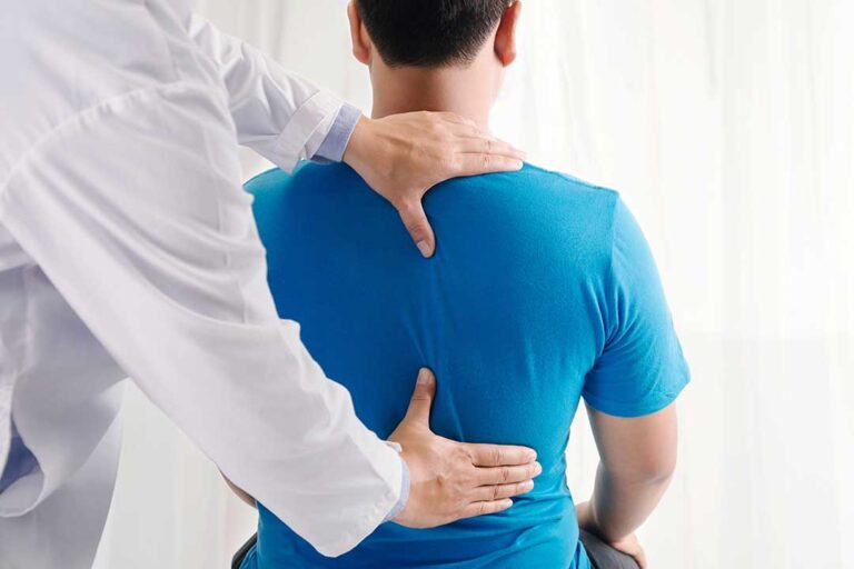 A chiropractor examining a patient’s back and neck in a bright health clinic setting.